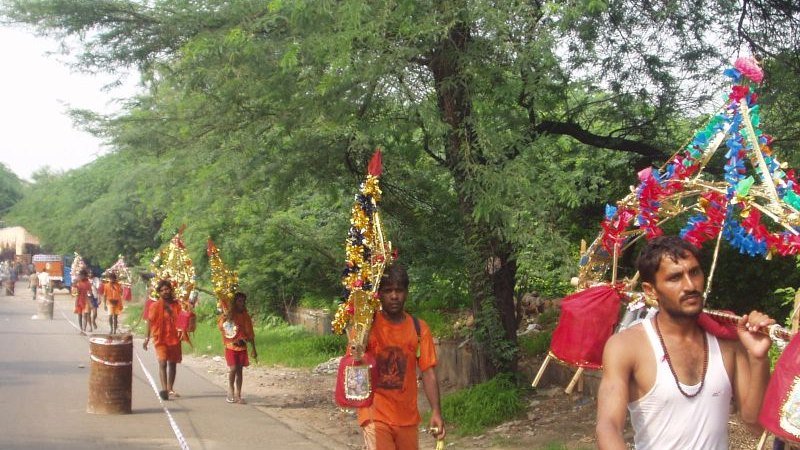 Kanwariyas in saffron carrying decorated kanwars along the road to Deoghar