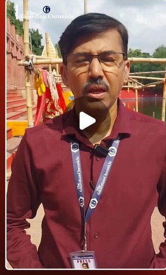 A Guardian Chronicle reporter presents to camera beside the steps of Shivganga pond in Deoghar