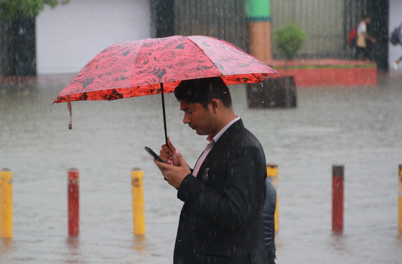 Waterlogged street in an urban area of Rajasthan with commuters navigating traffic during heavy monsoon rainfall.