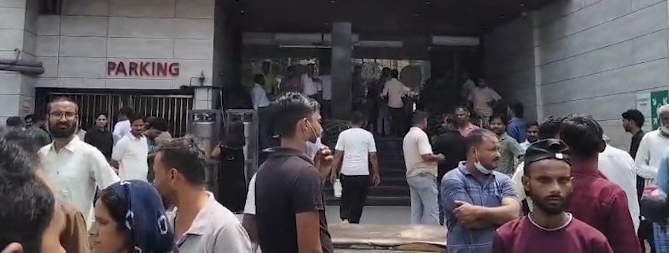 : Emergency personnel and hospital staff wheeling patients on stretchers outside a hospital building amid smoke during a fire rescue operation.