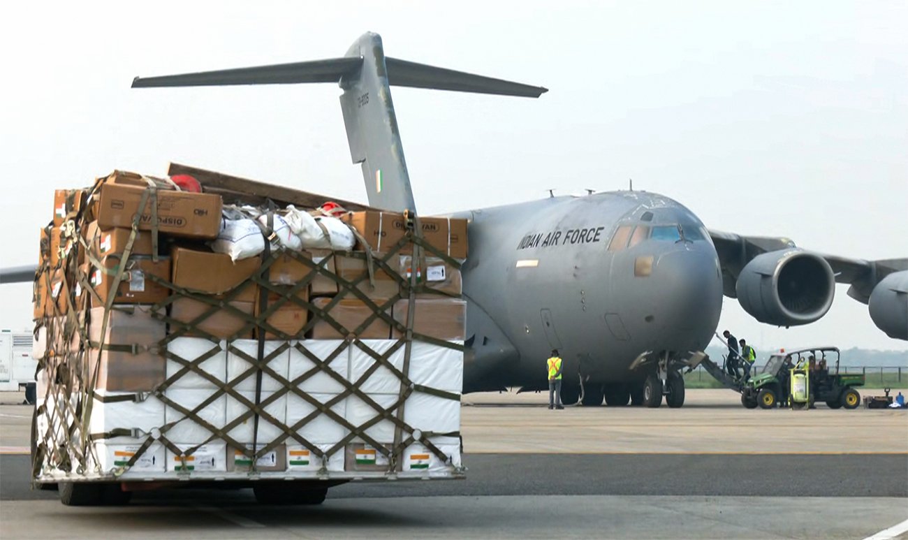 Indian Air Force personnel loading pallets of emergency medical supplies and food packets into a military transport aircraft at Hindon Airbase.