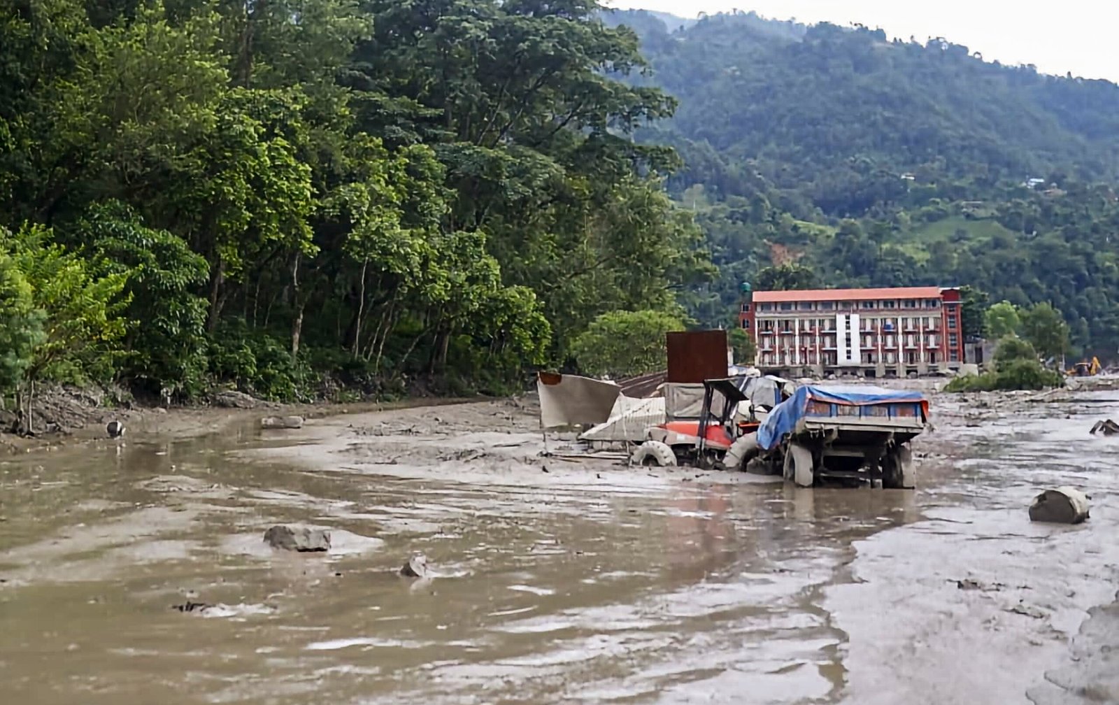 Devastating aftermath of flash floods along the Bhotekoshi River in central Nepal showing damaged infrastructure and rescue teams at work.