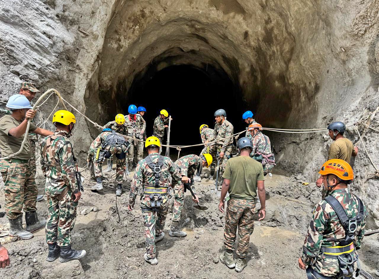 Emergency rescue personnel conducting search operations for missing victims along the flooded riverbanks in Nepal.